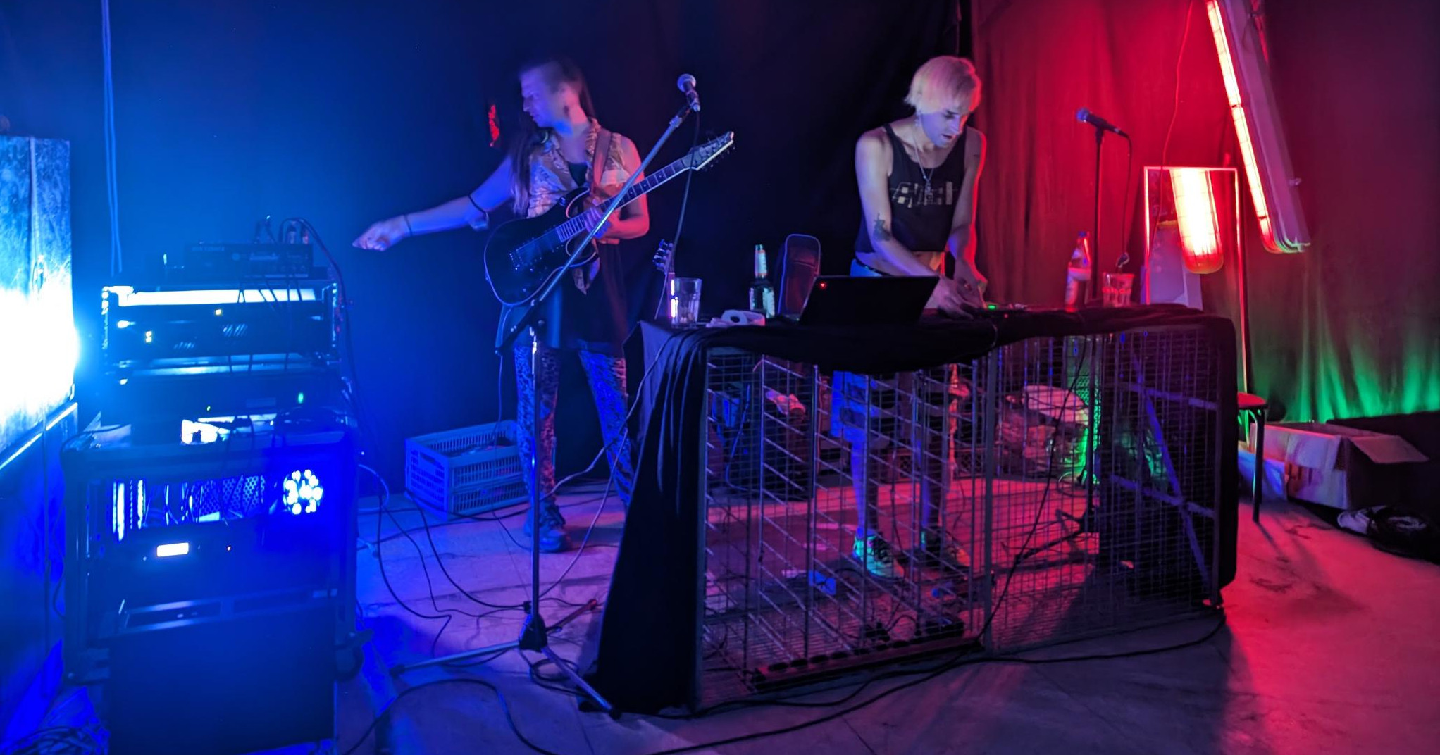 Nami und Phant mit ihren Instrumenten im Veranstaltungsraum, von rotem, blauen, und grünem Licht angeleuchtet.