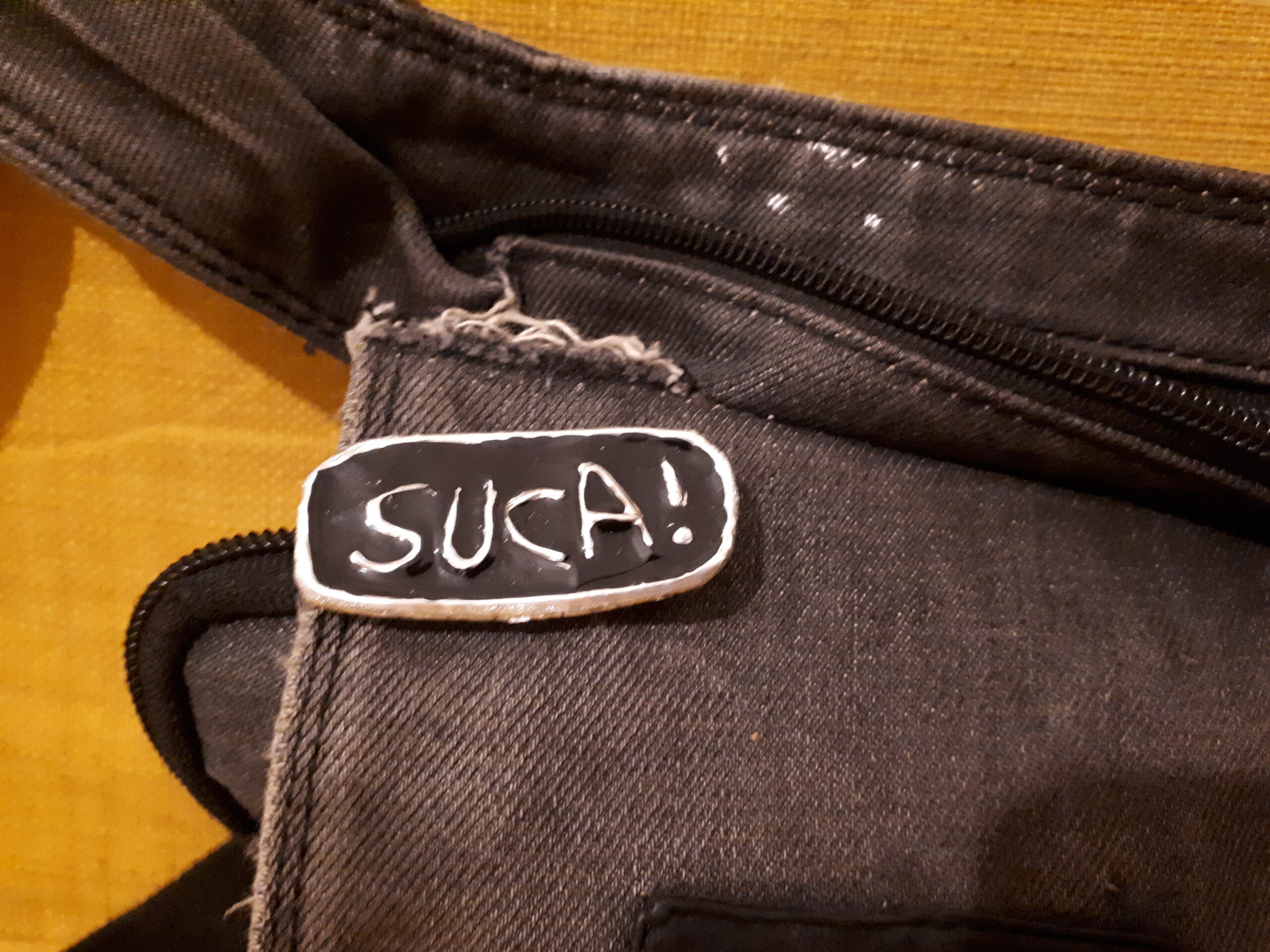 Ein Anstecker auf einer Bauchtasche, mit der Aufschrift "Suca!"